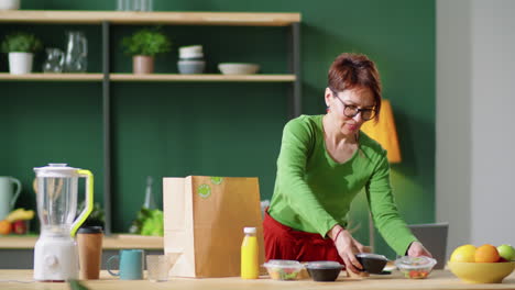 Middle-Age-Woman-Unloading-Healthy-Meals-and-Drinks-from-Paper-Bag